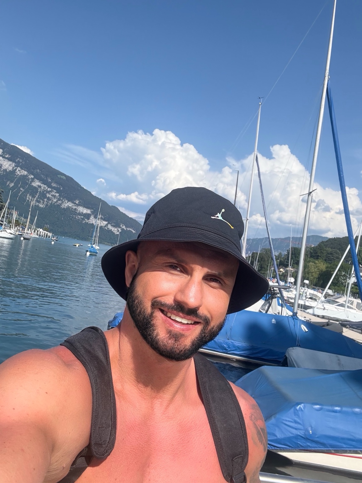 Dawid by a lake with sailboats and mountains
